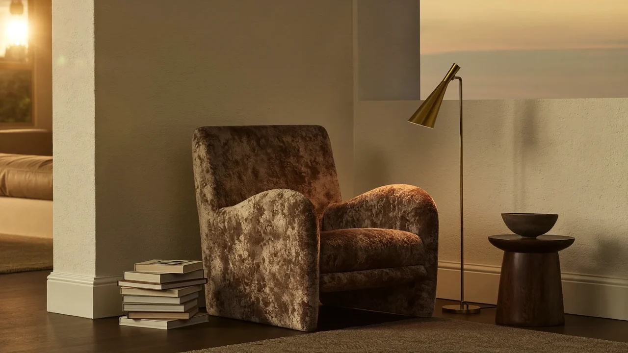 Færdigt hjørne med læsestol, standerlampe, bøger og keramikskål i lampelys